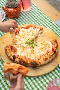 a freshly baked sourdough pizza served on a rustic board on top of a green and white checked tablecloth