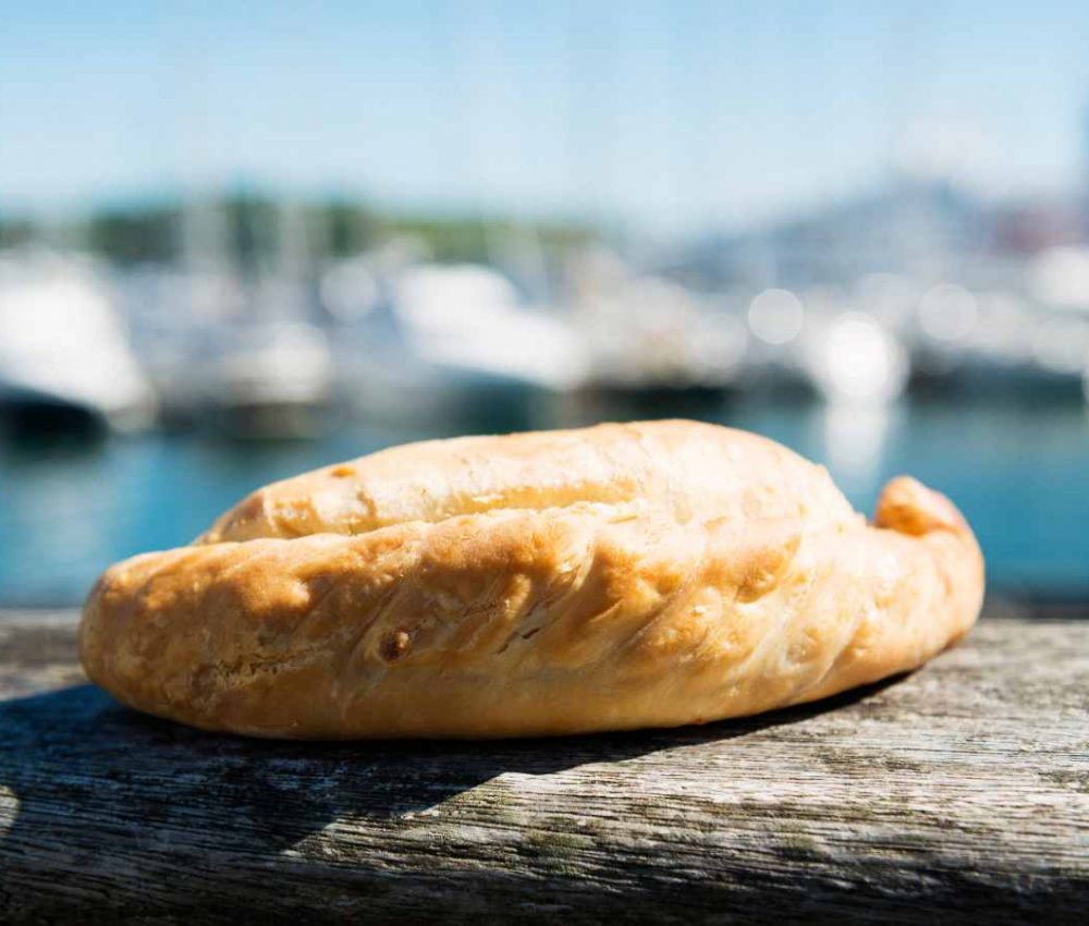 a Cornish pasty photographed outside on a sunny day at the beach in Cornwall
